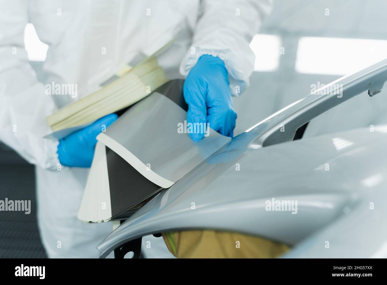 Auto painter selecting color with paint samples of car body element at