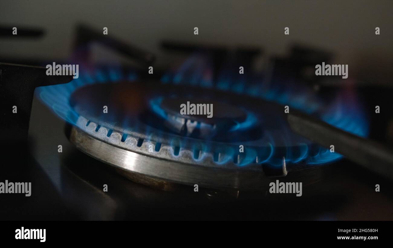 The burner of a gas stove with a bright flame of natural gas. Kitchen burner turning on, close