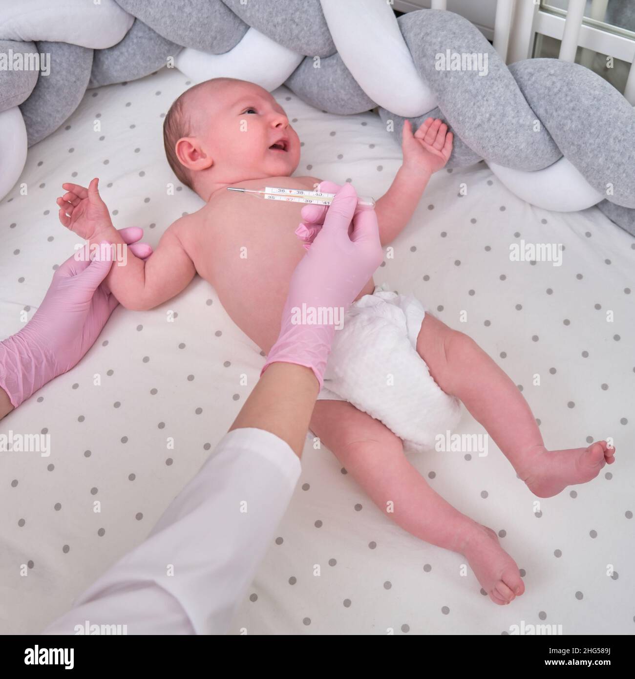 Doctor checks the temperature of the newborn baby with a thermometer. A