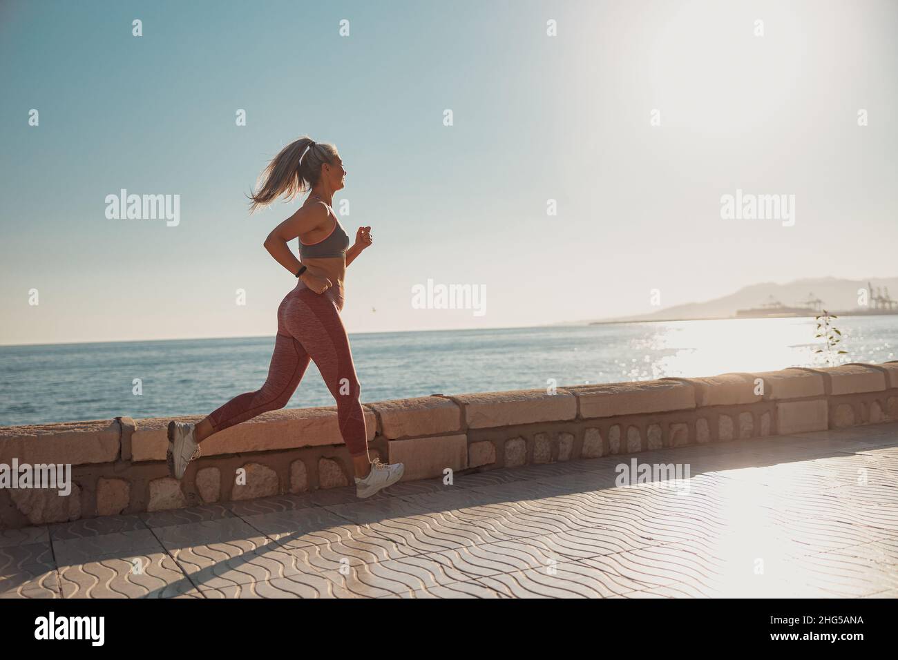 Sporty lady actively jogging by the waterfront Stock Photo