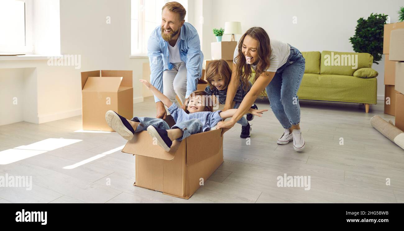 Happy young family playing with boxes and having fun in their newly bought house Stock Photo