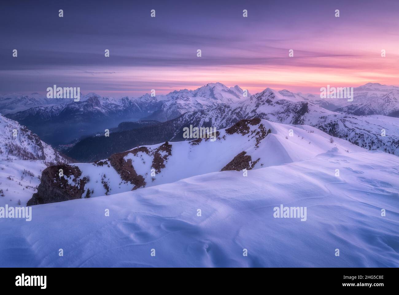 Snow covered mountains and purple sky with clouds at sunset Stock Photo