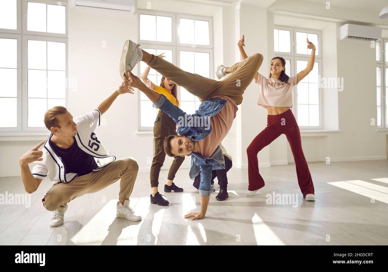 Energetic male dancer has fun with his dance group doing elements of breakdance movements. Stock Photo