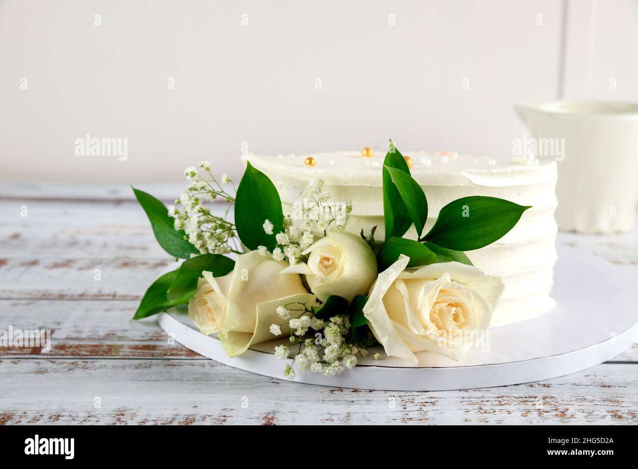 Beautiful wedding cake with white roses on white background. Stock Photo