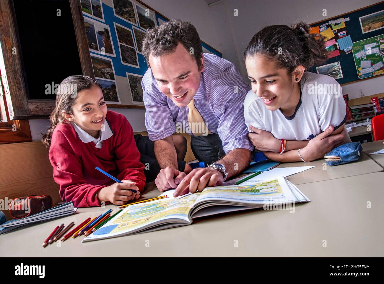 Teacher and junior school pupils 9-11 years in window lit school classroom relaxed happily interacting together on a geography mapping project Stock Photo