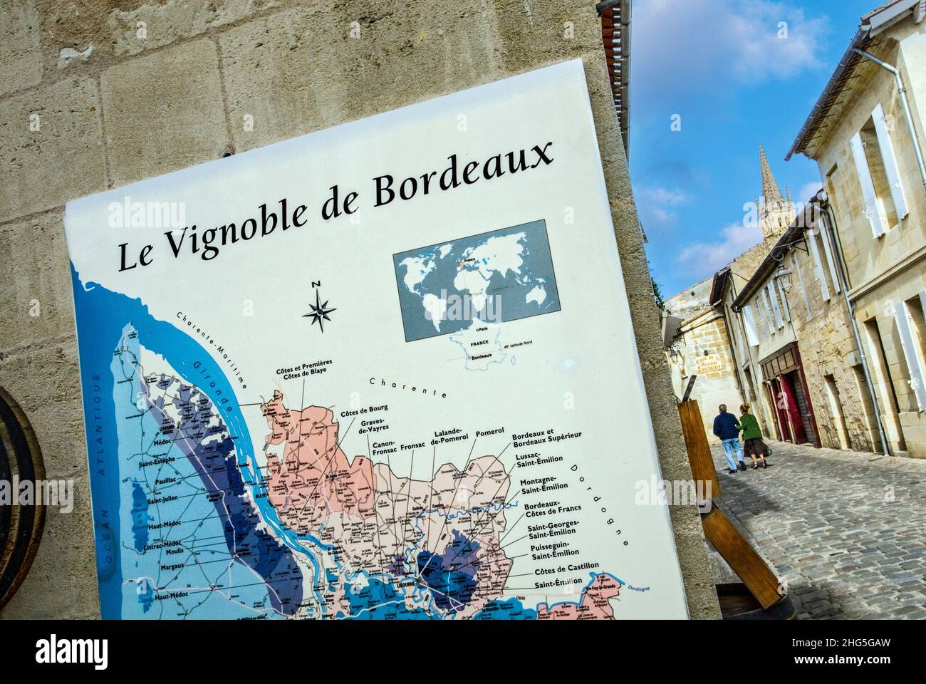 Wine map of Bordeaux area on wall of Saint Emilion wine shop with couple behind exploring historic village of Saint  Emilion Gironde Bordeaux France Stock Photo