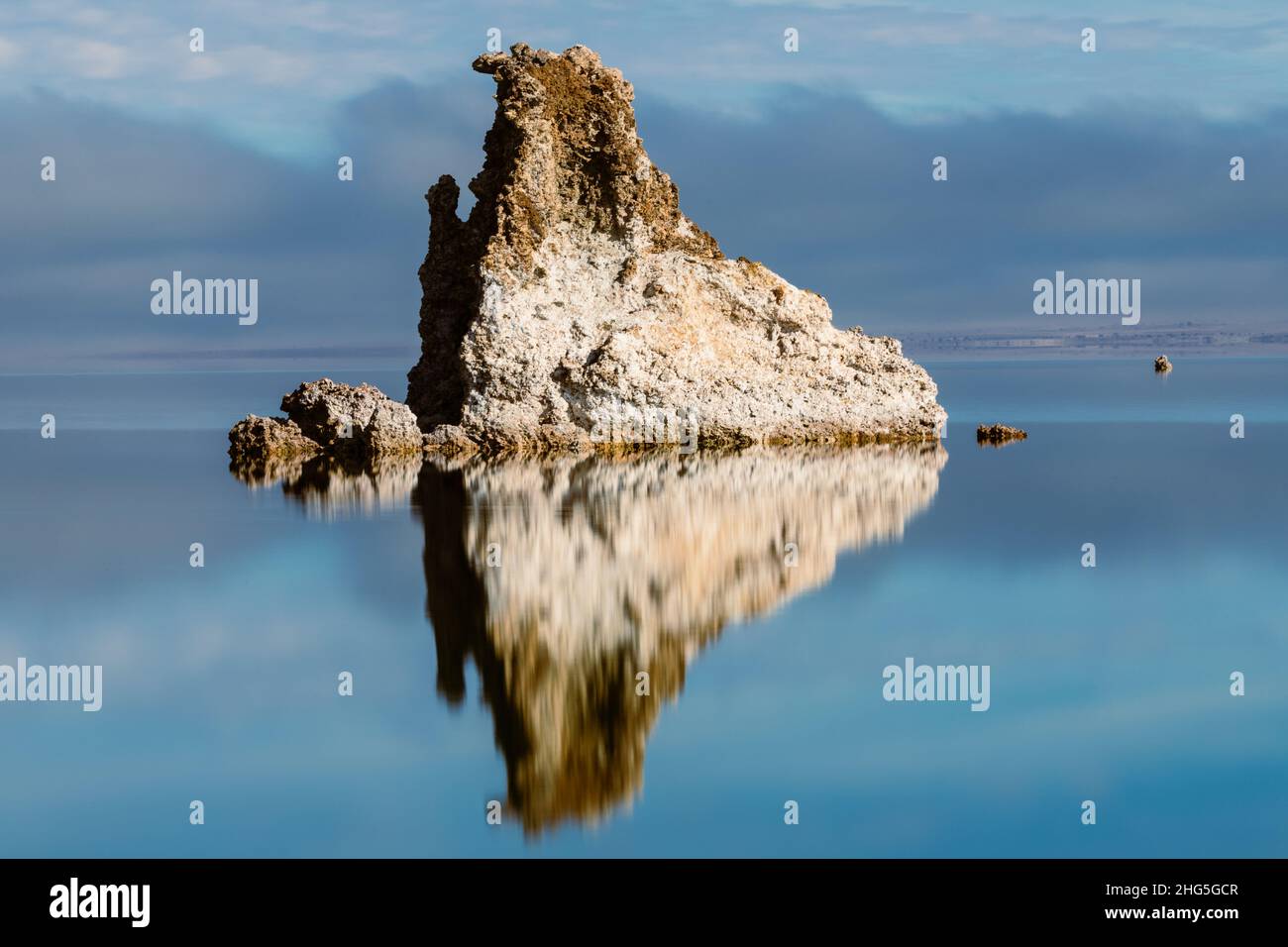 Large tufa formation in Mono Lake in Mono County, California, USA.   Image features reflections in calm water and low clouds/fog in the background. Stock Photo