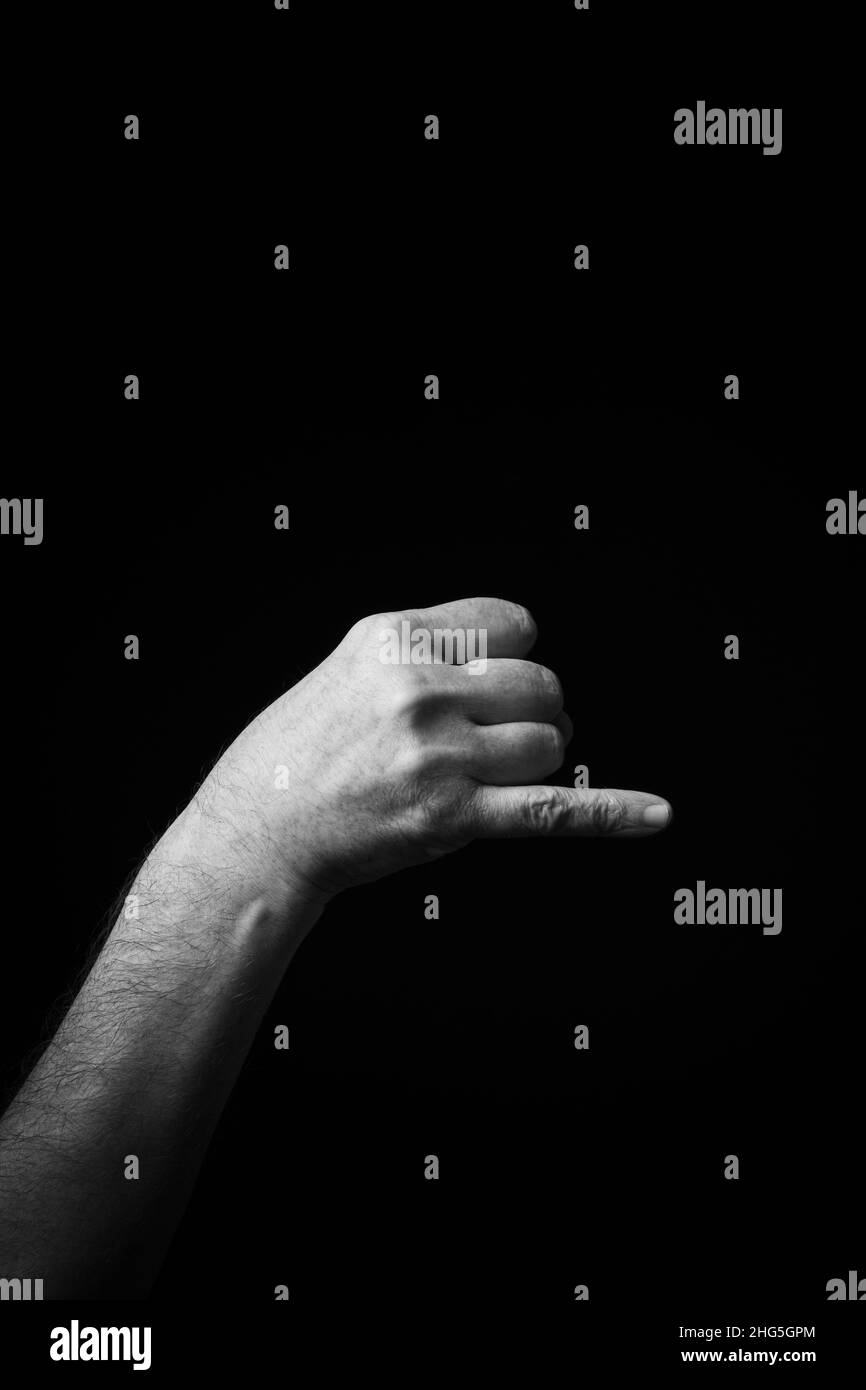 Dramatic B+W image of male hand fingerspelling CSL Chinese sign language letter NG isolated against dark background Stock Photo