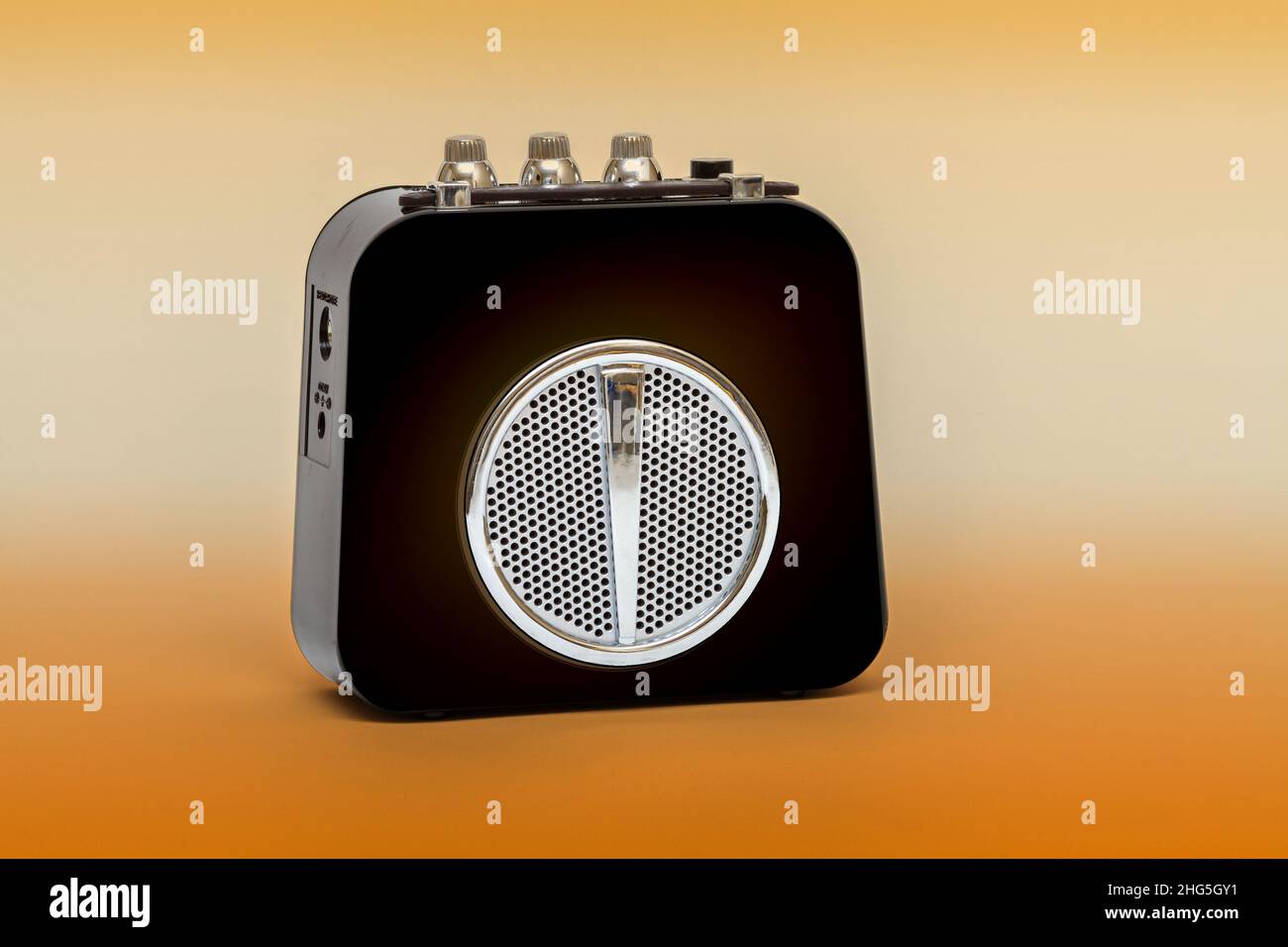 Small black guitar amplifier with orange background Stock Photo