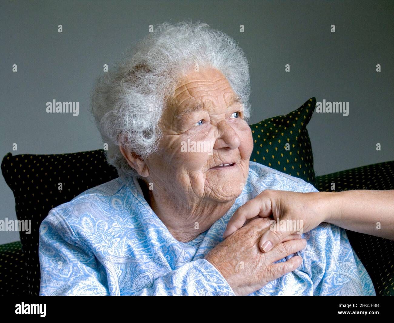 Elderly lady hands holding cared for in her old age, senior woman relaxed content secure woman holds comforting hand of carer nurse companion in her day living room in natural light Stock Photo