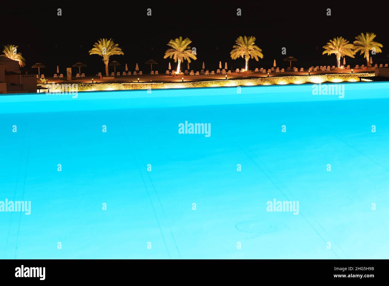 The swimming pool and beach at luxury hotel in night illumination, Ras Al Khaima, UAE Stock Photo
