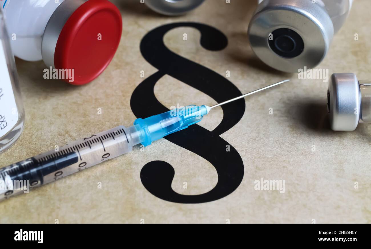 Closeup of paragraph symbol with vaccination syringe and vials - mandatory vaccination concept (focus on blue part of syringe) Stock Photo