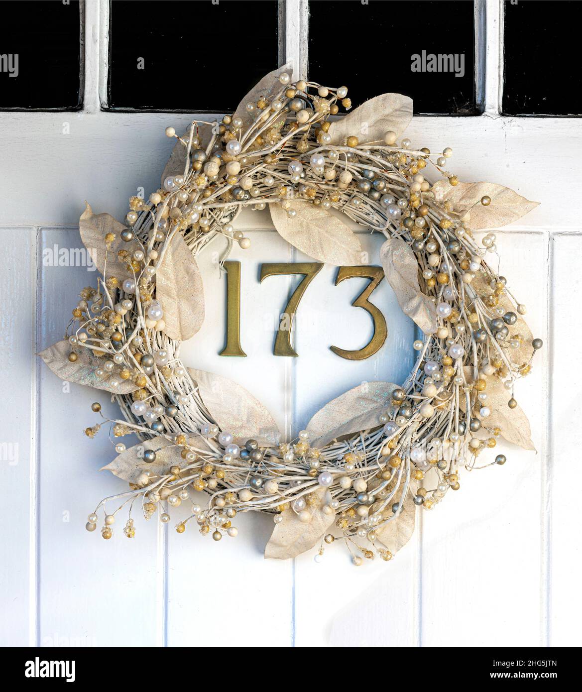 Traditional christmas holly wreath hanging on front door of 19th century cottage - Berkshire, England, UK Stock Photo