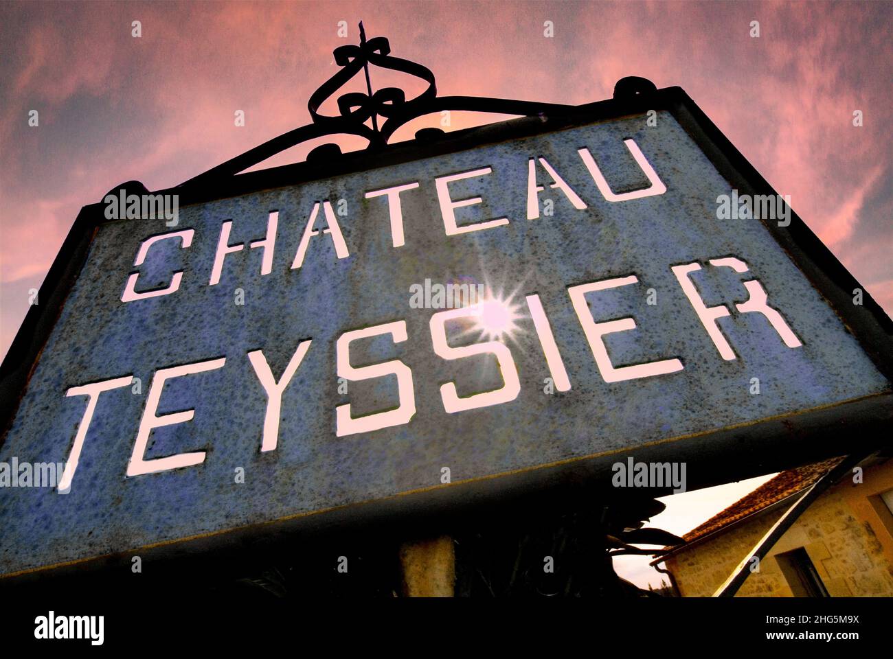 CHATEAU TEYSSIER Weathered metal plaque with sunburst, at red sunset outside Château Teyssier a Bordeaux wine producer from the appellation Saint Emilion Grand Cru. Metal sign in the vineyard at sunset Chateau Teyssier Vigonet Saint Emilion Gironde France Stock Photo