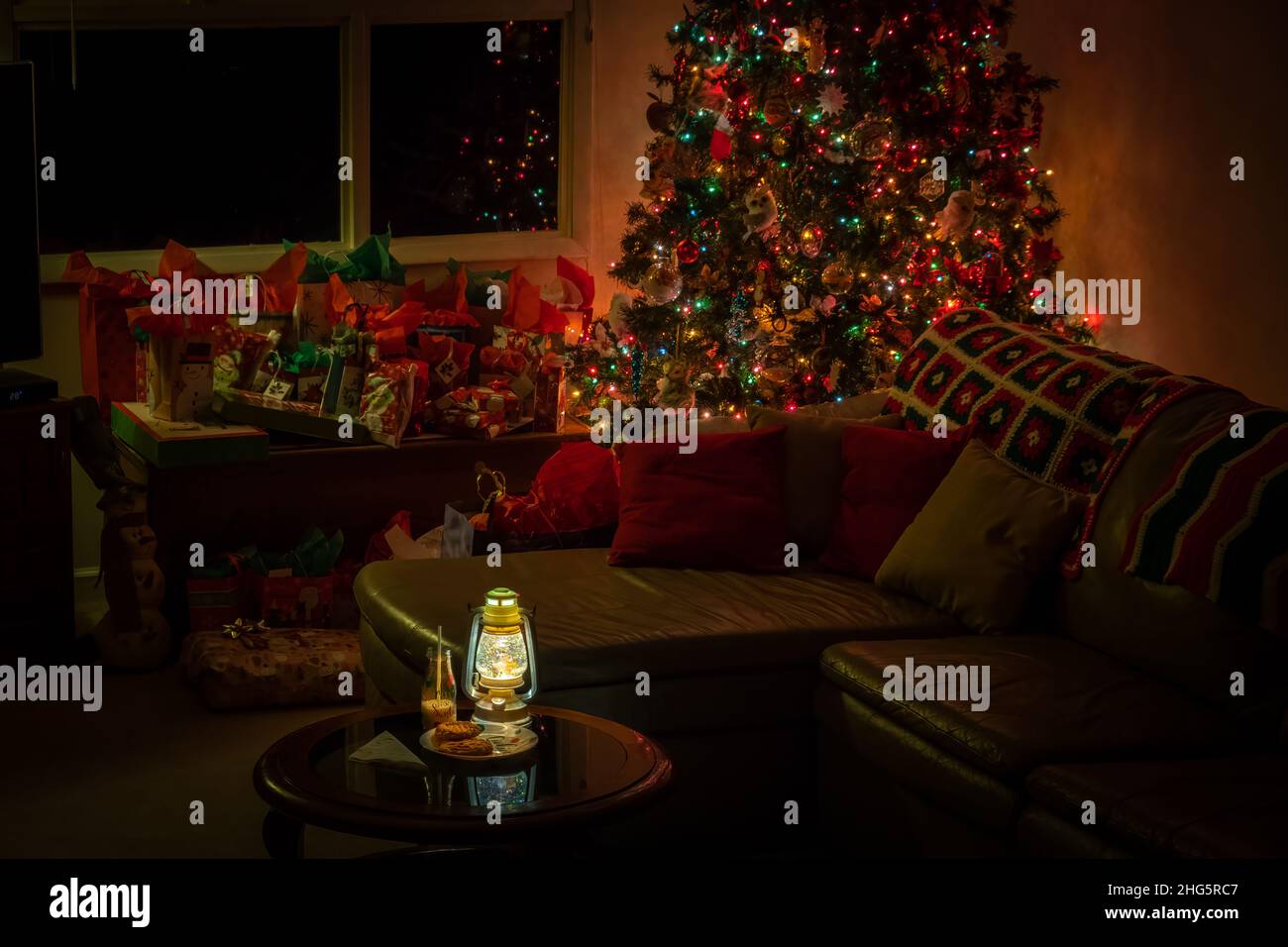 A nighttime living room Christmas scene with a decorated tree, presents, and milk and cookies for Santa. Stock Photo