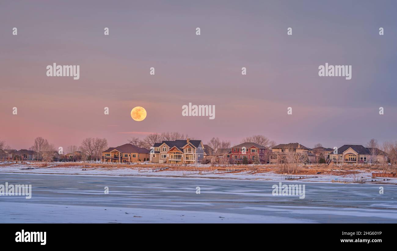 full moon rising over houses at waterfront of Boyd Lake in northern