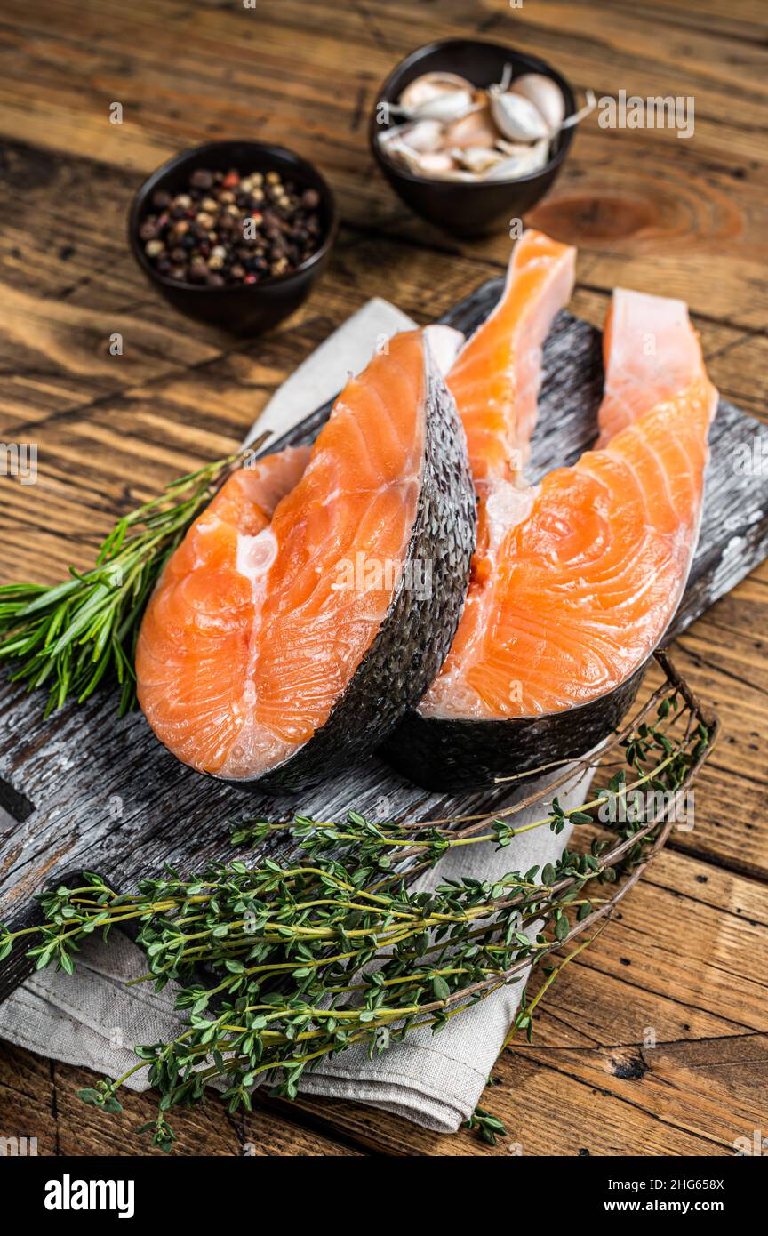 Raw Salmon steaks on a wooden cutting board with thyme and rosemary ...