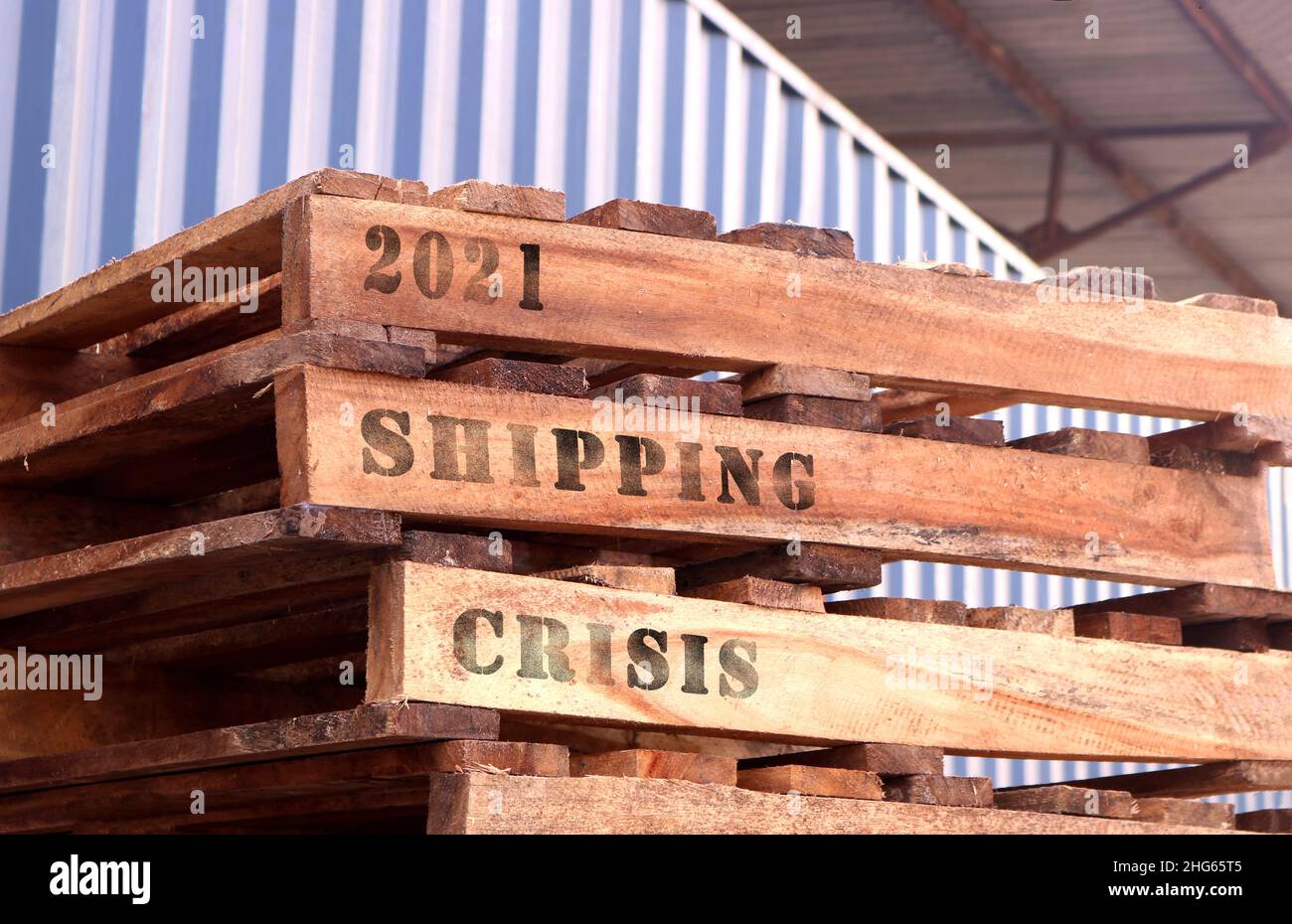 '2021 Shipping Crisis', text written on piled up pallets. Supply chain concept Stock Photo