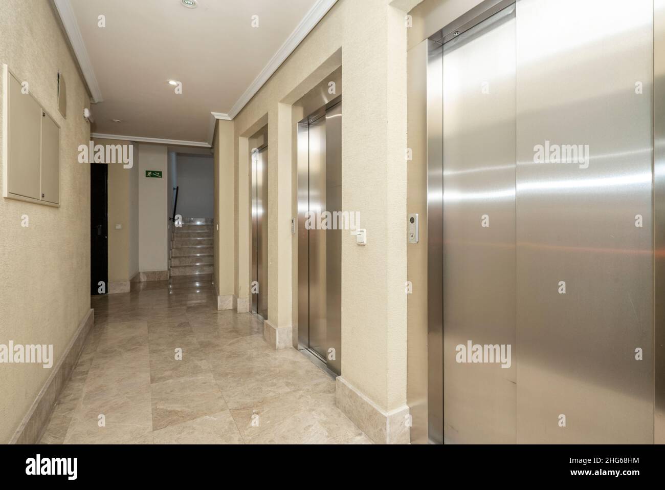 Lobby of a building with three elevators with cream marble floors Stock Photo