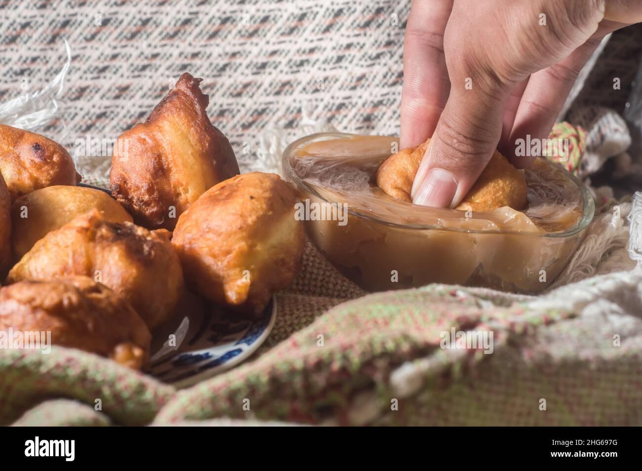 brazilian sweet called 'bolinho de chuva' rain dumpling, or Fritter, in a natural home environment copy space and hands holding a dumpling Stock Photo