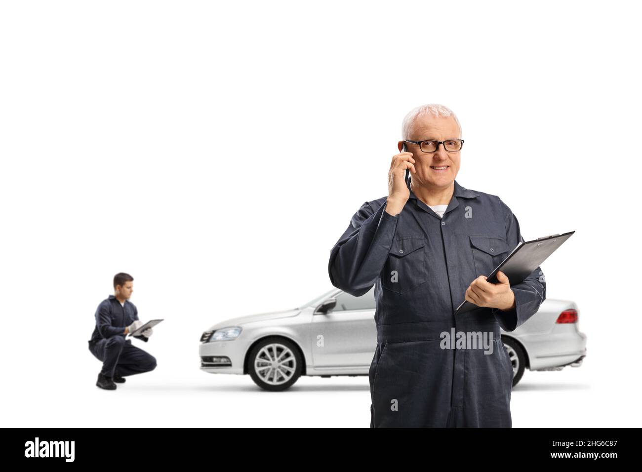 Car mechanic making a phone call and holding a clipboard and other
