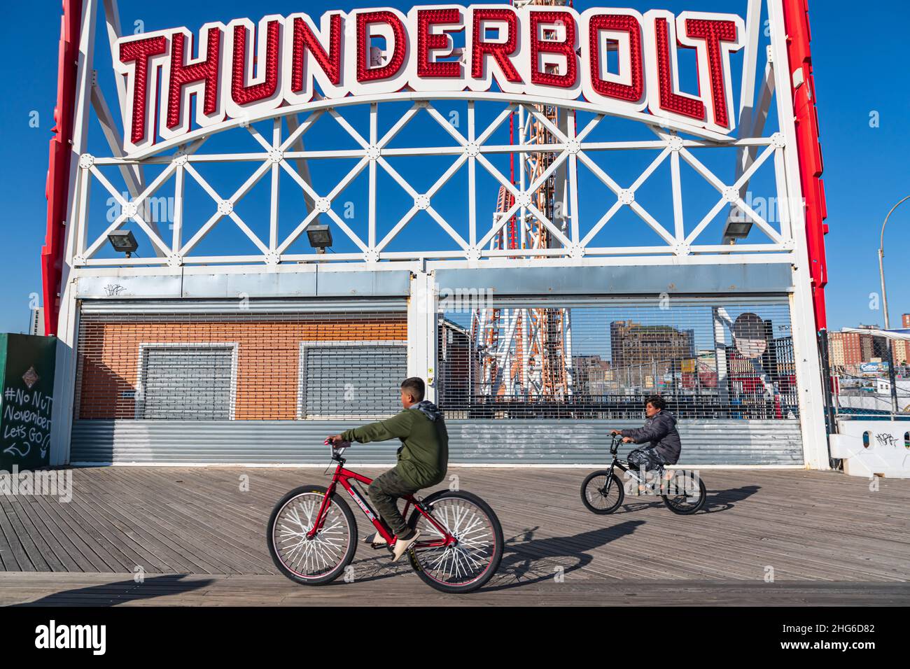 Coney Island, Brooklyn, New York City, New York, USA. November 6, 2021. Boys on bikes in front of the Thunderbolt ride at Coney Island. Stock Photo