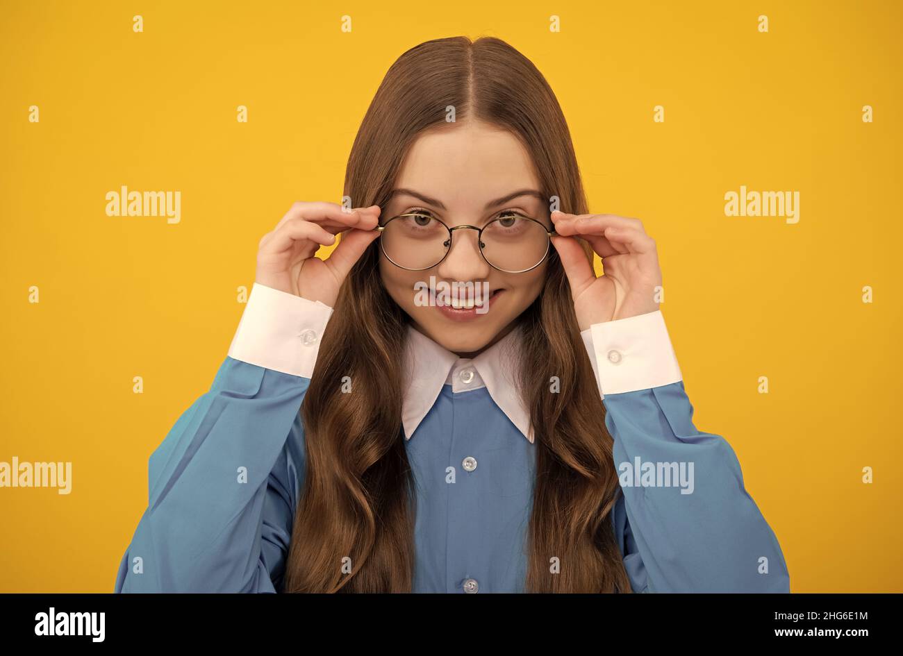 Happy school age girl child fix eyeglasses yellow background, eyesight Stock Photo