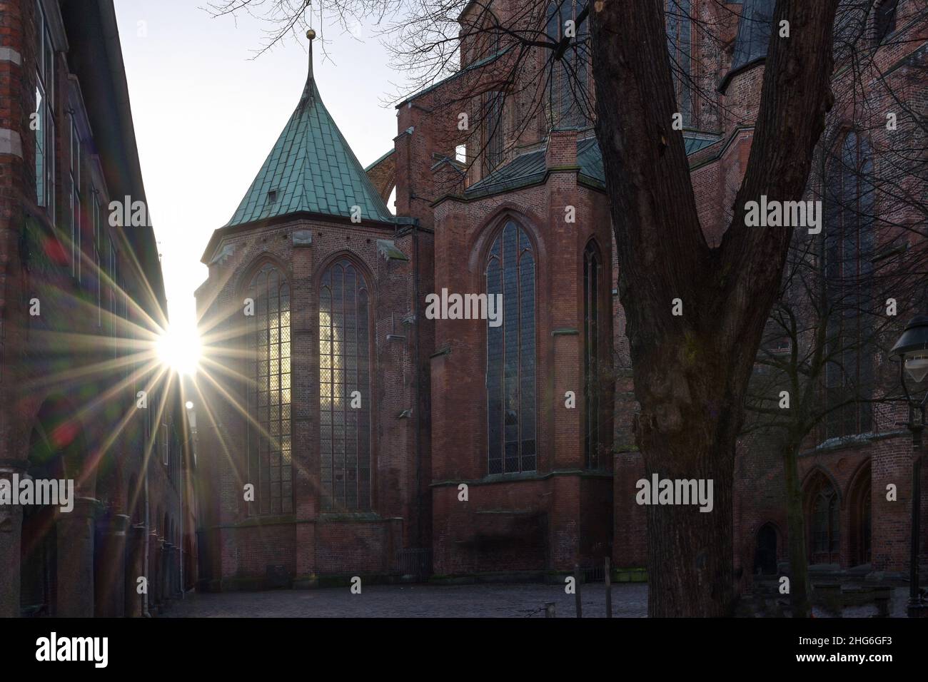 Sun star with lens flares at the historic Marienkirche (St. Mary's church) of Lubeck in Germany, a famous basilica made of red bricks, landmark and to Stock Photo