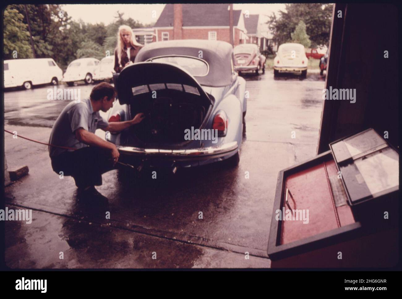 Service Station Mechanic Adjusts the Engine for a Young Woman Whose