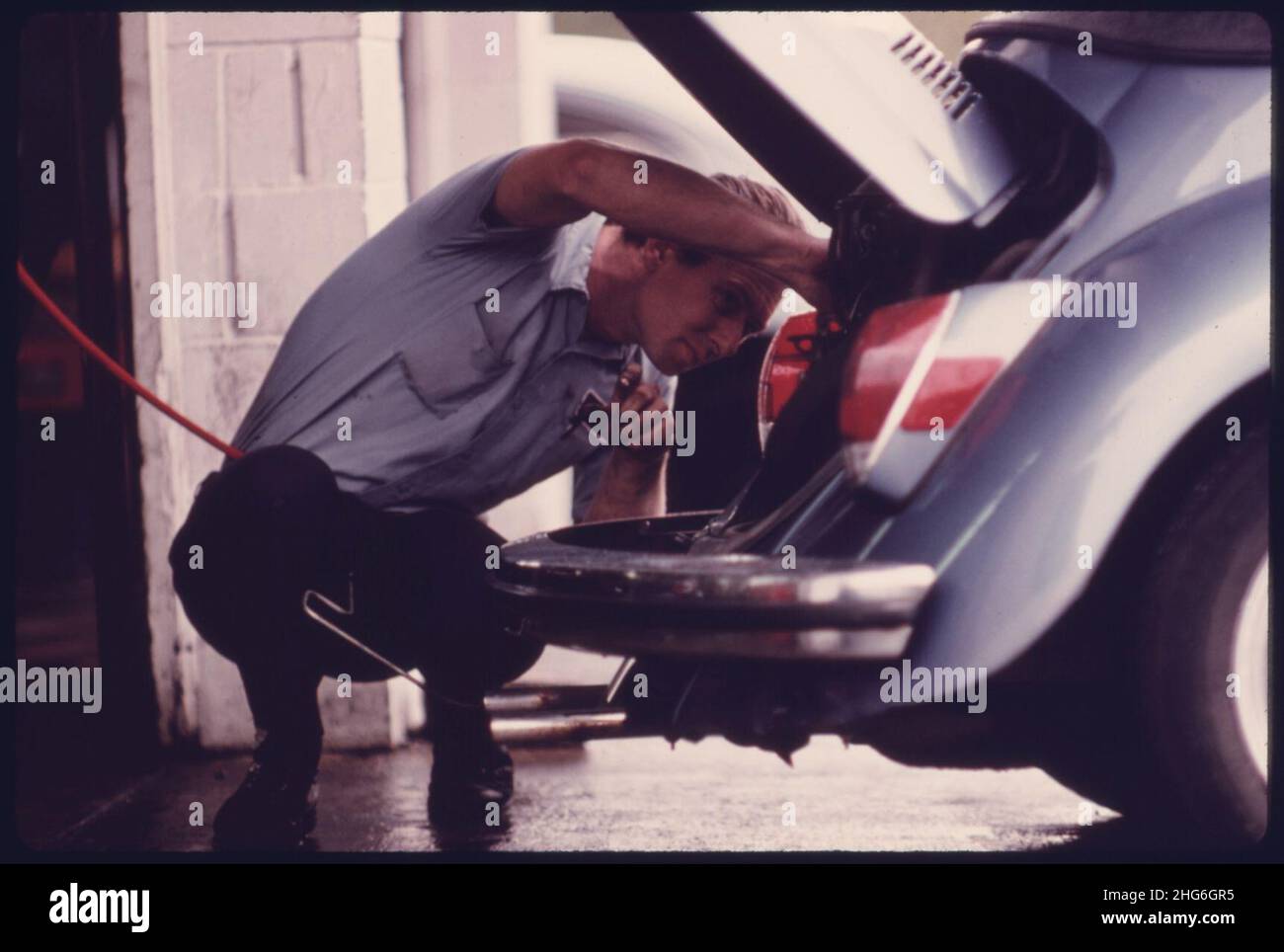 Service Station Mechanic Adjusts the Engine for a Young Woman Whose