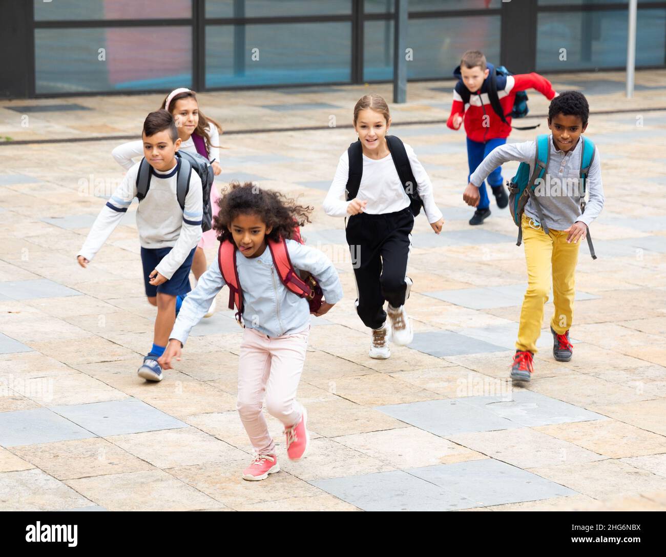 Group of cheerful tweenagers running in school yard after lessons Stock Photo