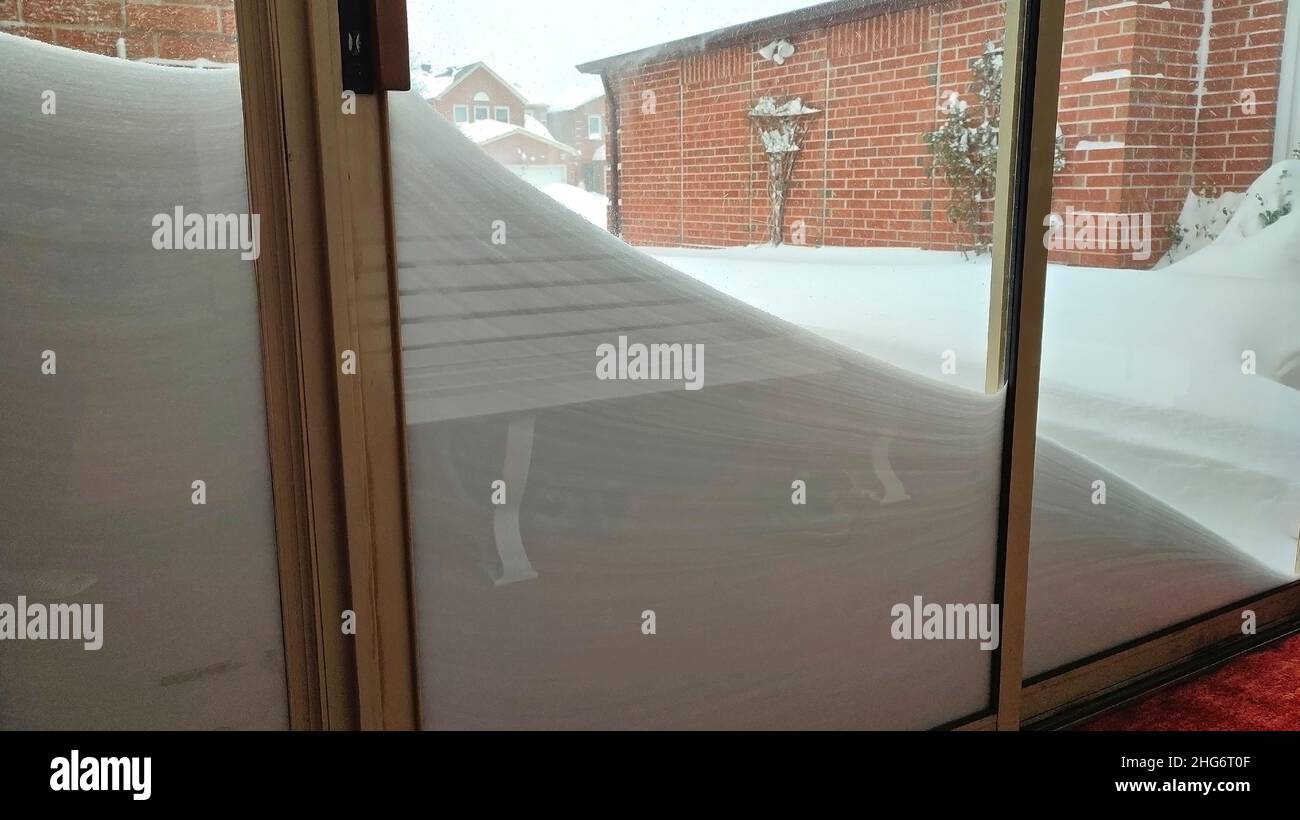 Snow-covered patio doors after winter storm. The glass patio doors are covered with deep white snow in Canada for a weather or blizzard concept. Stock Photo