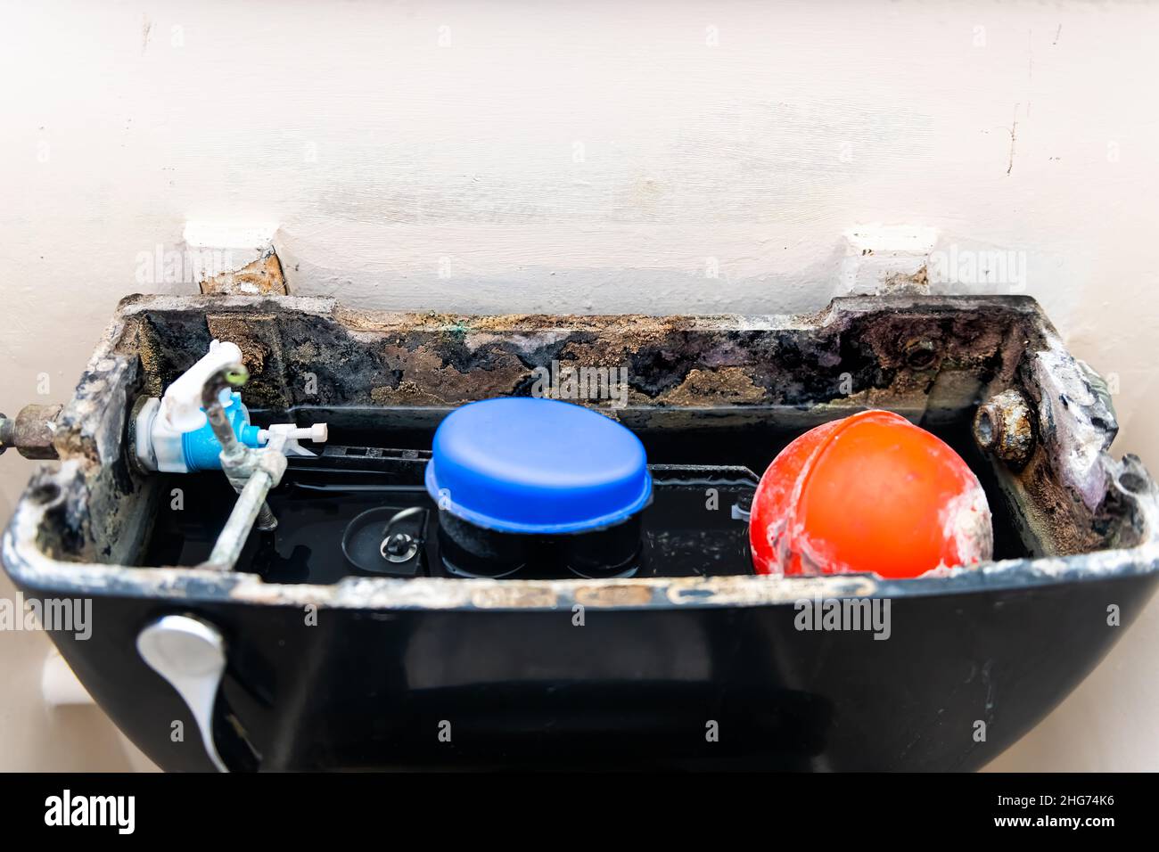 Open inside broken toilet closeup with rust soiled dirty old material object pump and water in small bathroom in London, United Kingdom Stock Photo