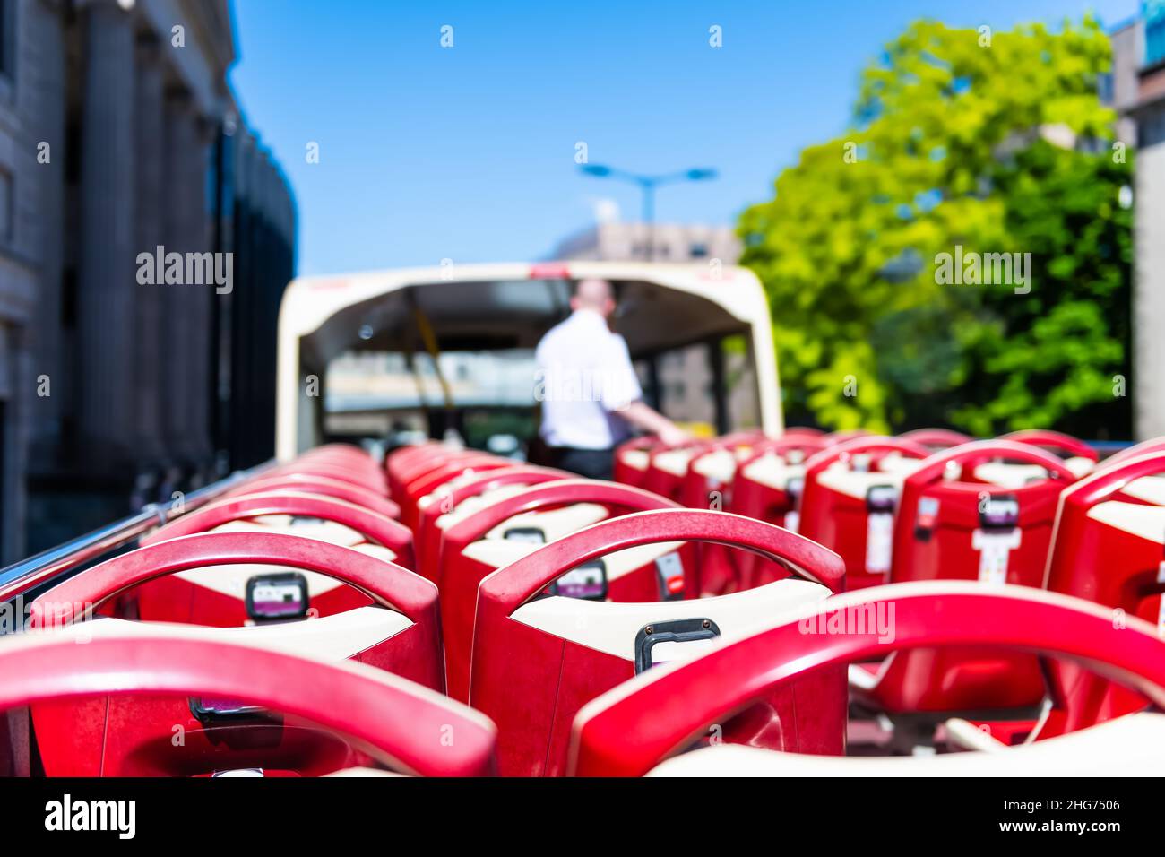 London, UK open top of red double decker tourist bus with guided tour guide riding through streets and empty chairs seats Stock Photo