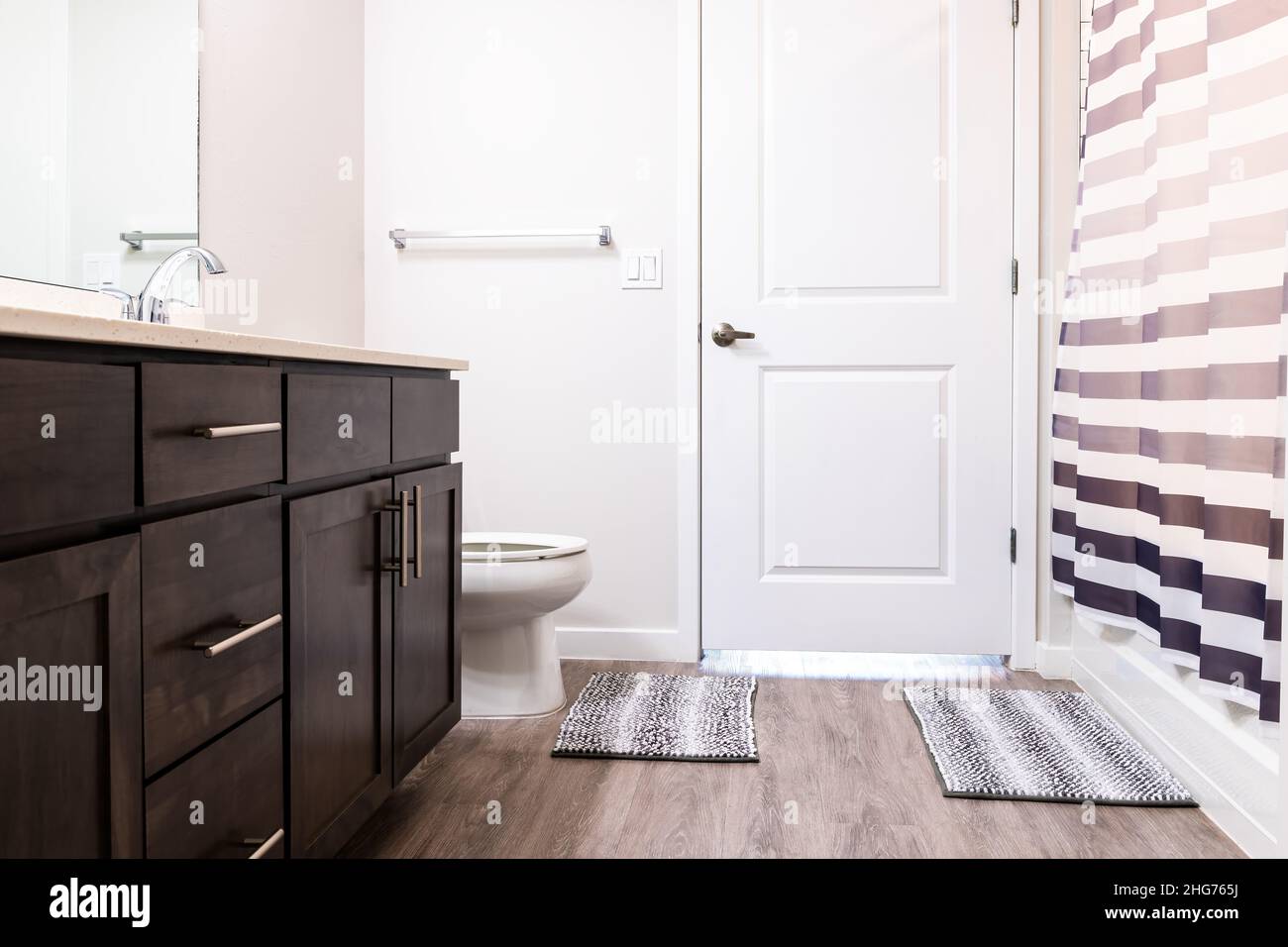 Empty bathroom interior nobody in new construction modern luxury apartment home house and white toilet with rug, door cabinets and shower bath curtain Stock Photo
