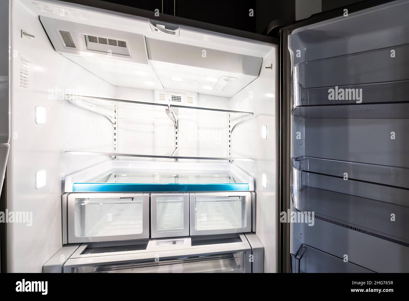 Interior closeup of empty modern luxury design French door fridge refrigerator with clean shelf shelves inside and no food Stock Photo