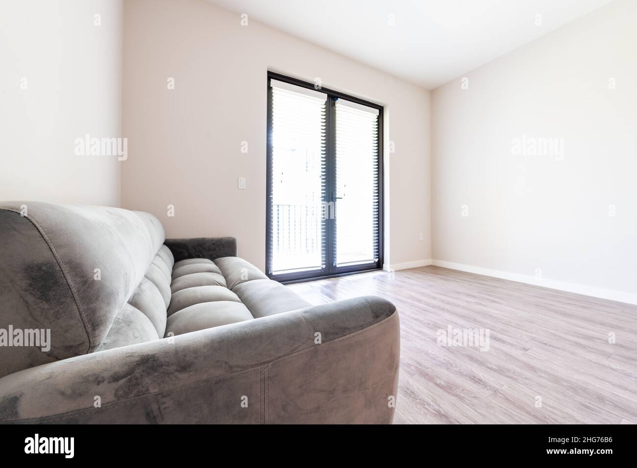 Empty living room interior with futon couch gray sofa furniture closeup in new modern apartment house with window doors balcony and natural light on h Stock Photo