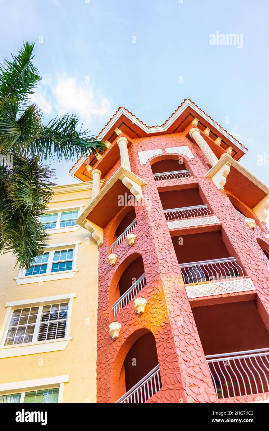 Colorful condo apartment balcony building with red yellow colors facade exterior windows and palm tree by expensive luxury real estate property in Flo Stock Photo