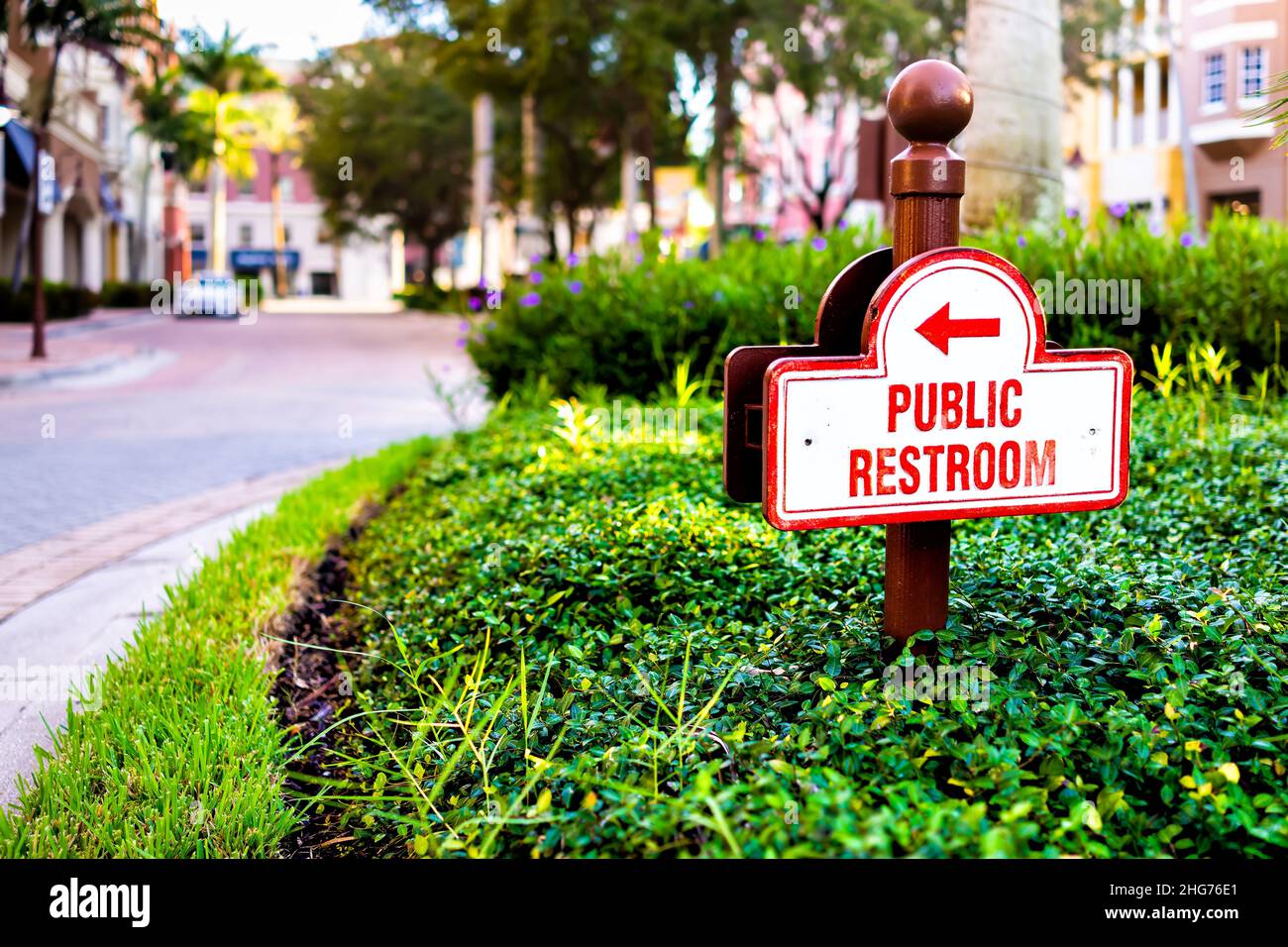 Naples, Florida residential street old town condo building community place with sign direction signpost for public restroom and nobody on road Stock Photo