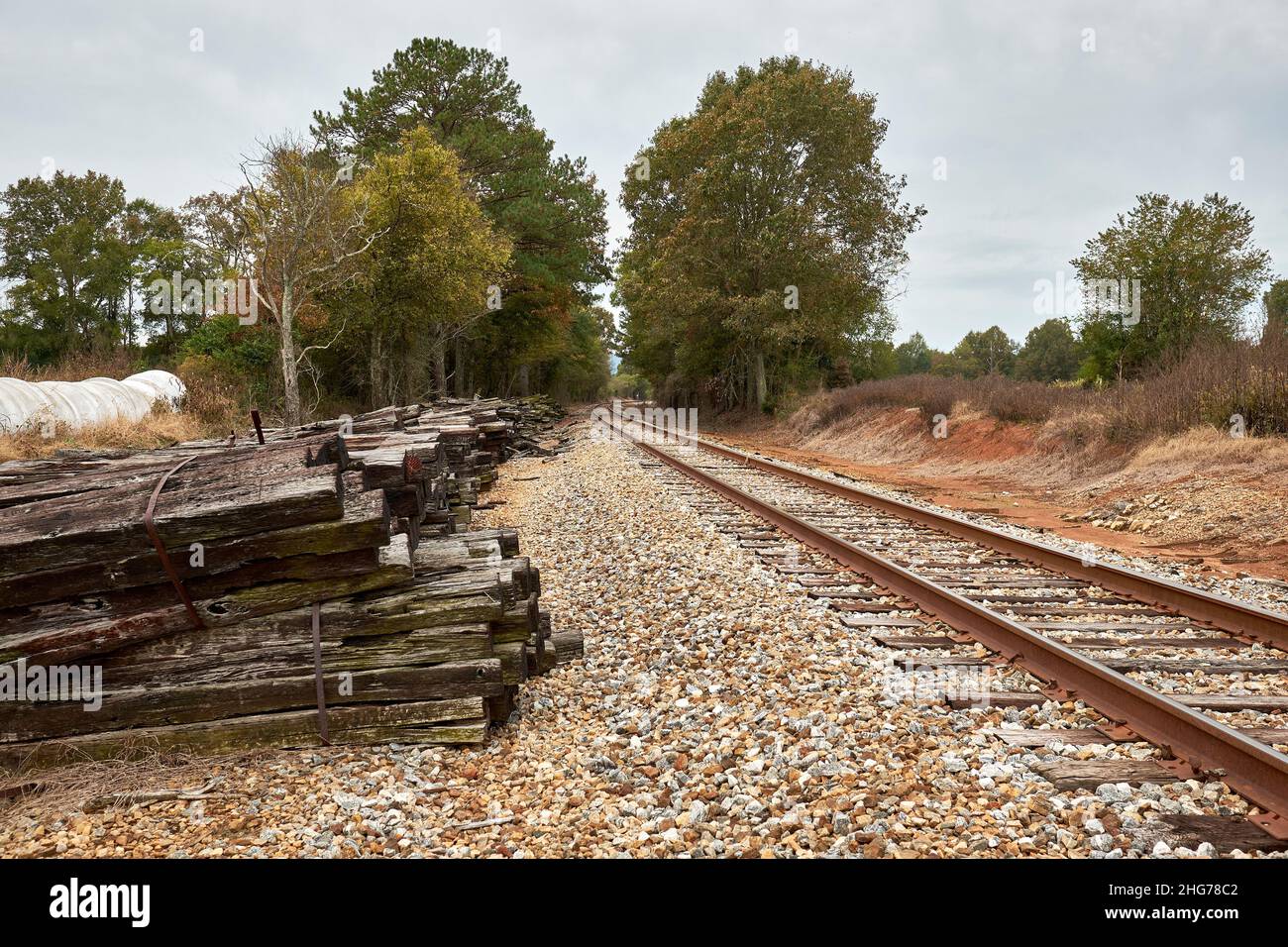 Railroad train tracks lead into the distance with old discarded used railroad ties next to the track in Alabama, USA. Stock Photo