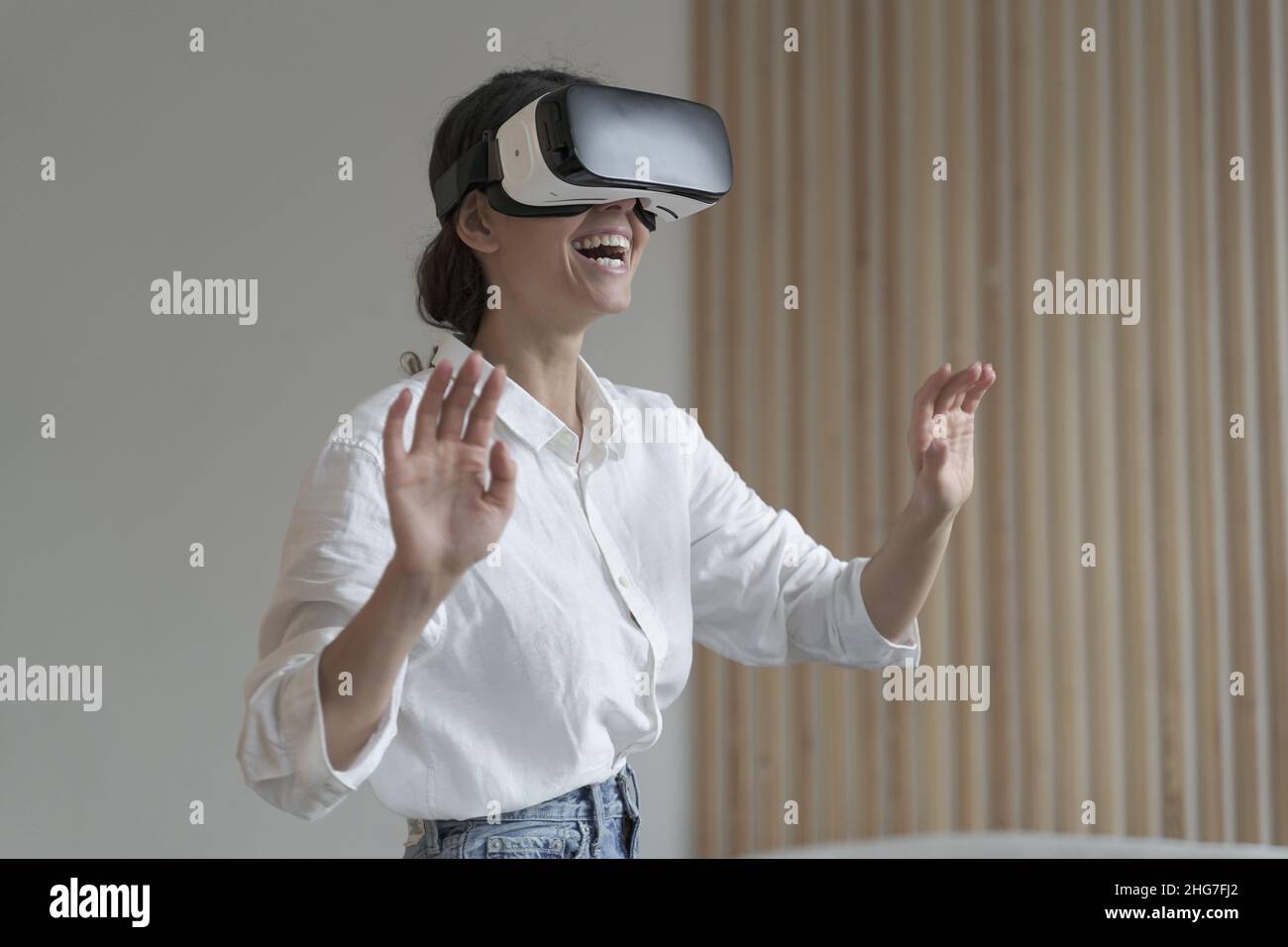 Impressed amazed female office worker using VR glasses while working in augmented reality world Stock Photo