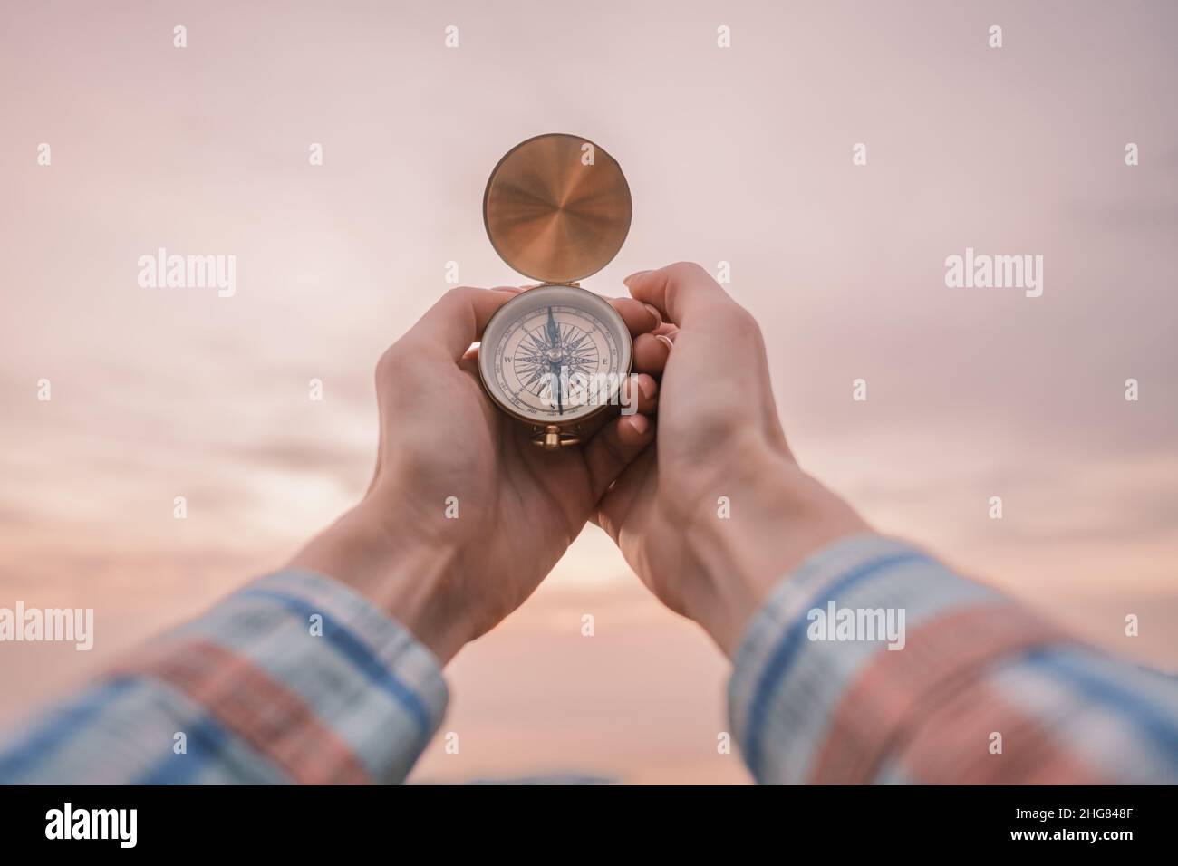 In female hands a vintage compass in the background of the sunset sky. Stock Photo