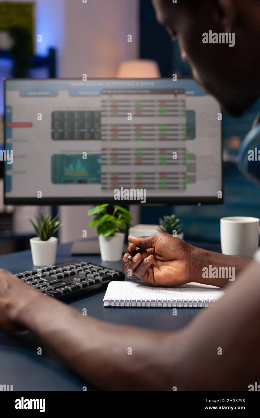close-up-of-entrepreneur-analyzing-numbers-of-stock-market-trade-writing-global-profit-on-notebook-in-living-room-freelancer-man-working-remote-from-home-thinking-to-invest-in-crypto-currency-2HG8798.jpg