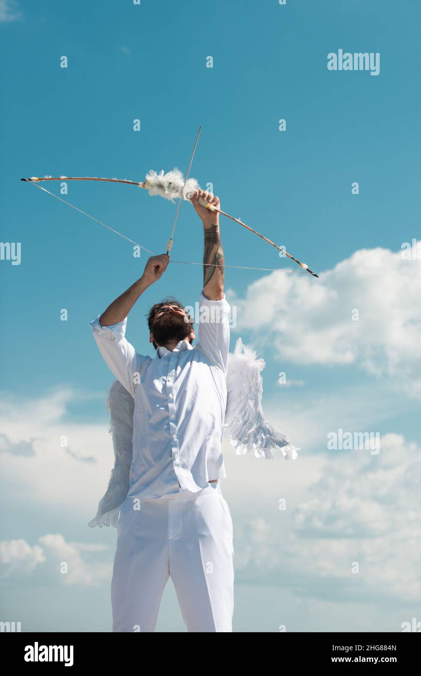 Funny cupid, handsome guy on valentine day with bow arrow shooting. Love concept. Handsome crazy fun angel. Bearded angel valentin man with angel Stock Photo