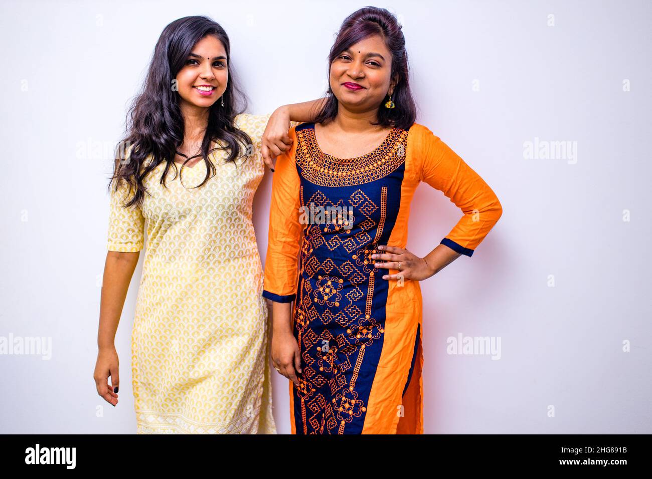 casual indian clothes ,two Indian woman in kurta posing over white wall Stock Photo