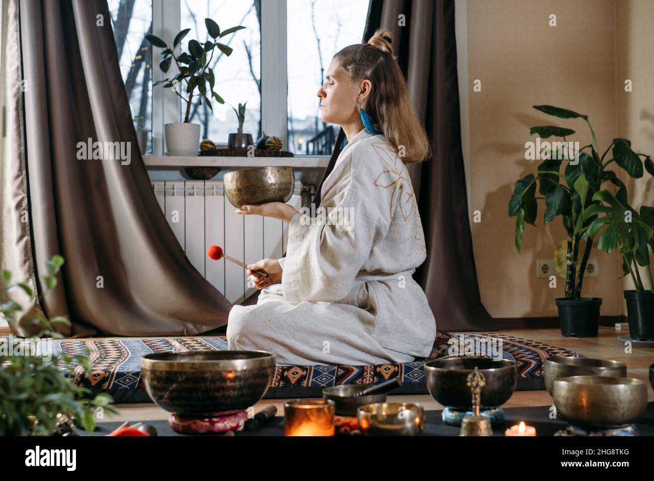 Sound healing with singing bowls, vibration massage and alternative treatment. Mental health care for adults. Woman in 40s playing to percussion Stock Photo