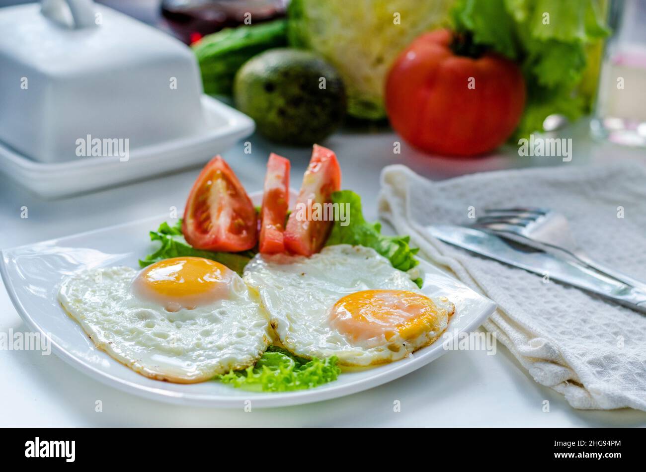 Fried eggs from two eggs on a plate with tomato Stock Photo