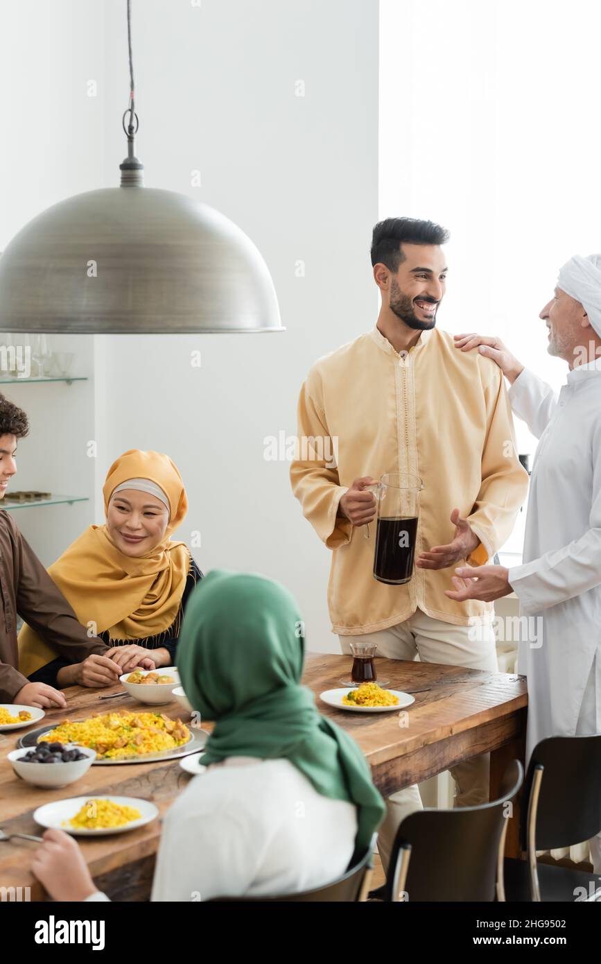 Mature man talking to araban son near interracial muslim family and food at home Stock Photo