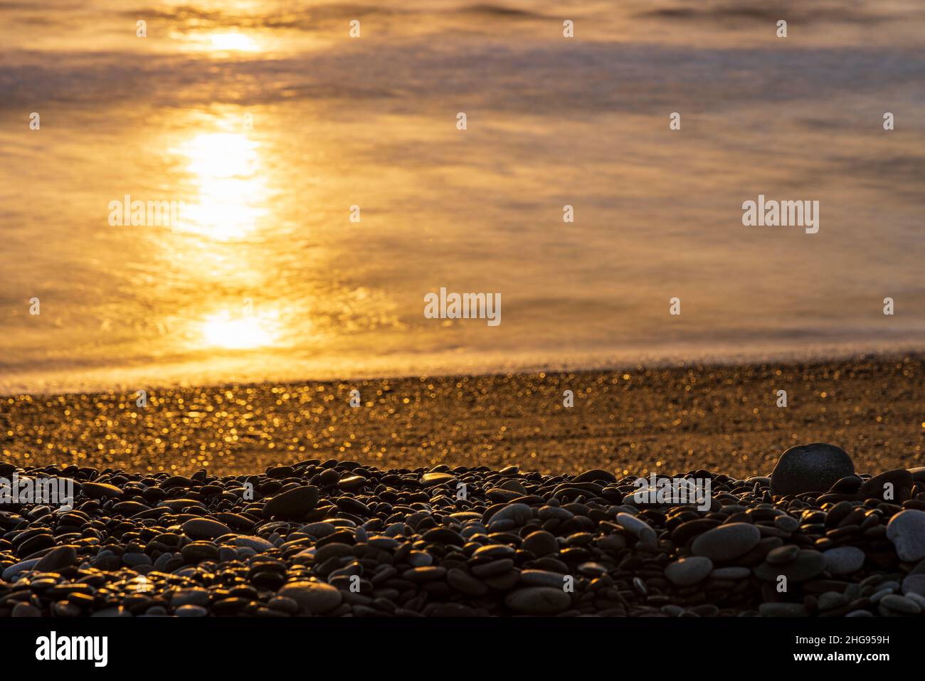 Early morning sun reflecting on the sea and stony beach at Tajao, Tenerife, Canary Islands, Spain Stock Photo