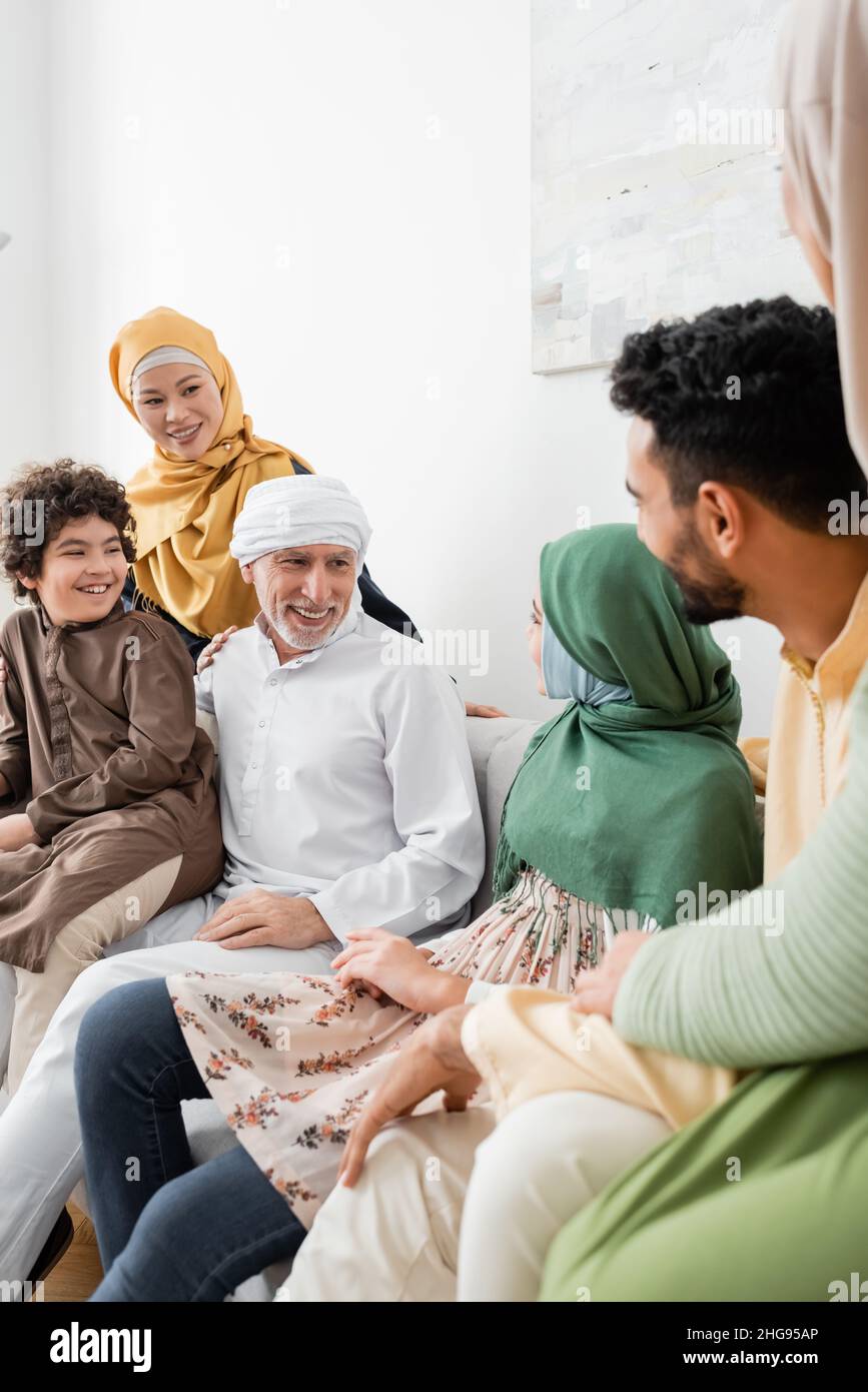 smiling muslim man talking to granddaughter near multicultural family Stock Photo